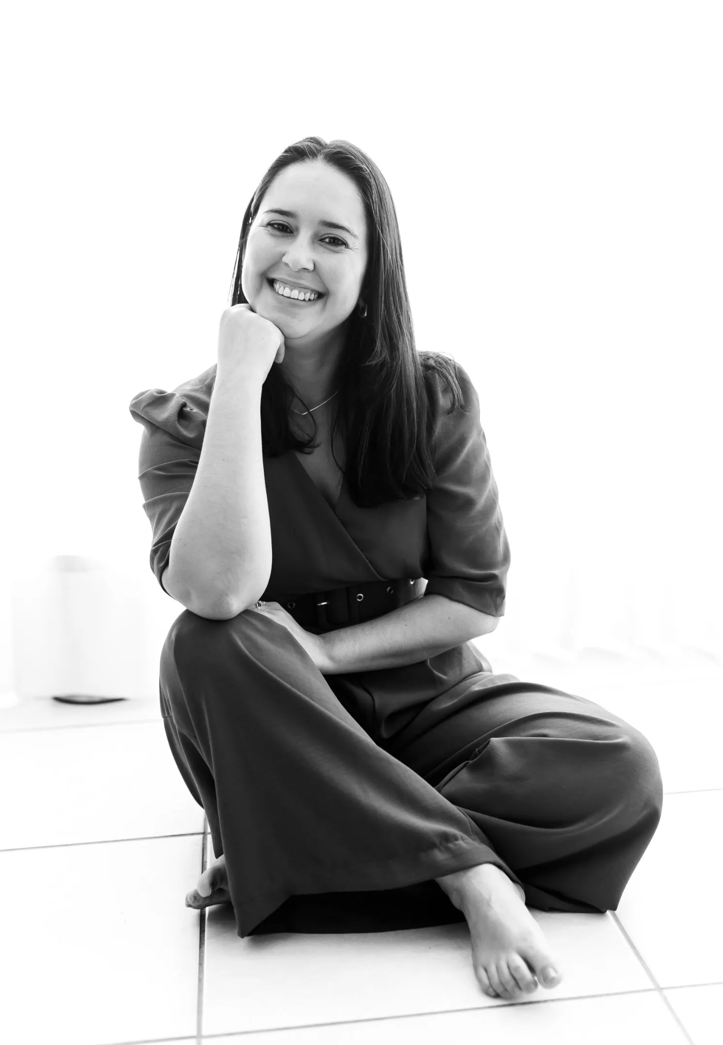 Retrato em preto e branco da Psicóloga Clínica Lizandra Coelho sorrindo, sentada de forma descontraída e acolhedora